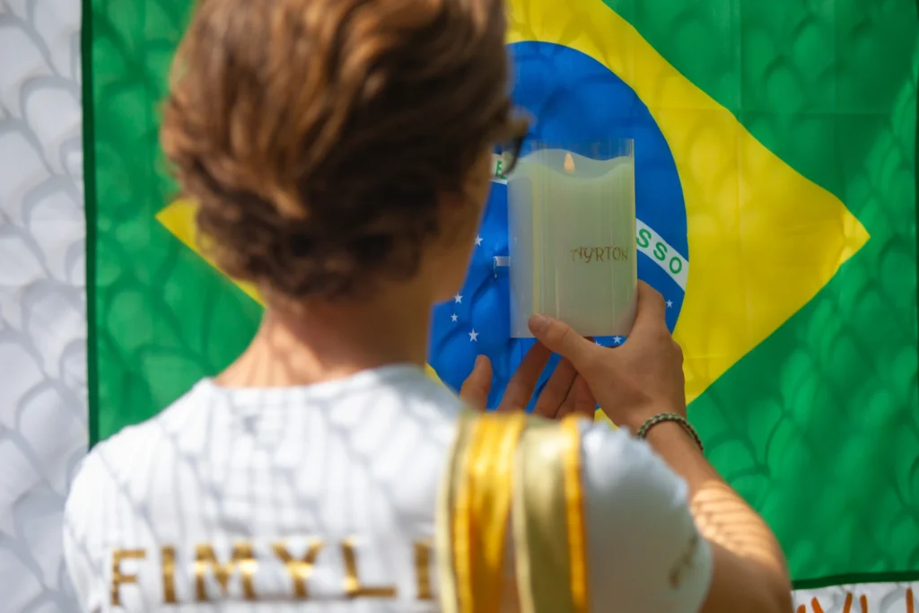 Un mensajero de Fimyli coloca una vela personalizada en la bandera brasileña de Senna en Imola