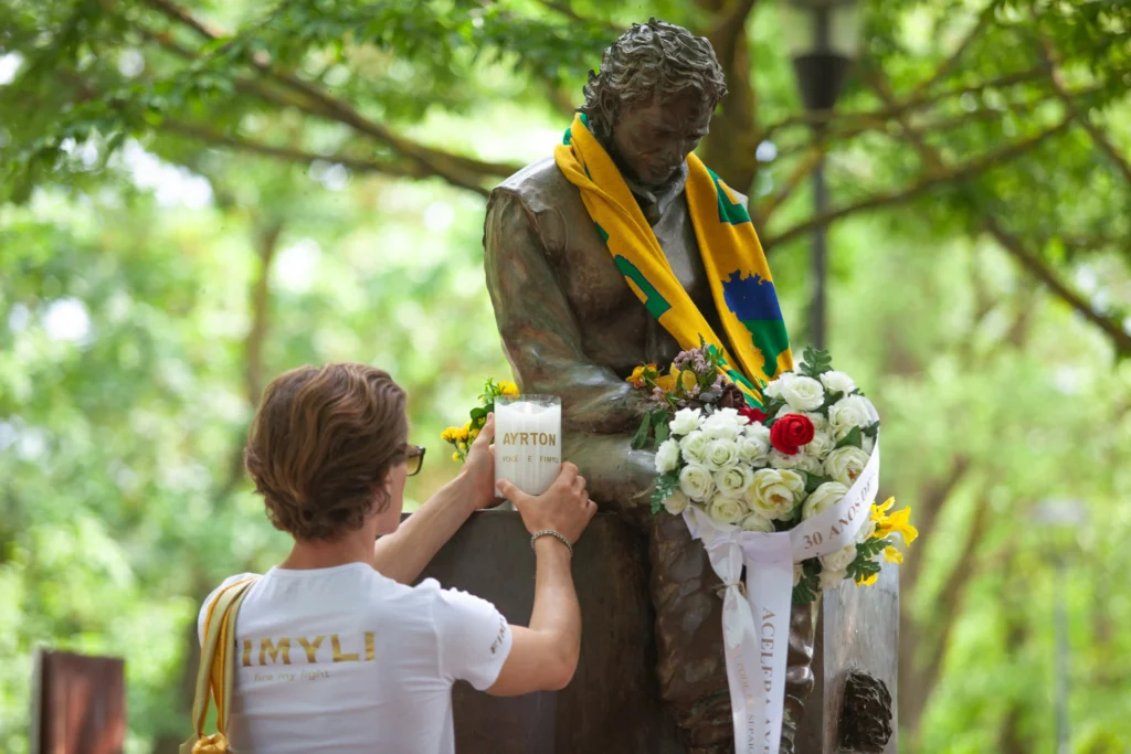 El mensajero de Fimyli enciende una vela conmemorativa en el busto de Ayrton Senna en Imola