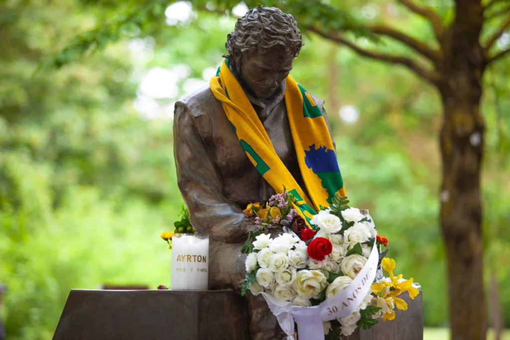 Busto de Ayrton Senna da Silva en Imola con vela Fimyli personalizada, ramo de rosas y pañuelo con los colores de Brasil